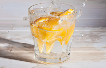 Refreshment Detox water with orange Cocktail with air bubbles and a splash on a white wooden background