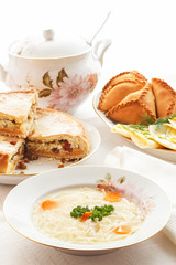 Traditional Tatar holiday table. Tokmach - noodle soup with chicken. Triangles - meat pies and sweet cake.
