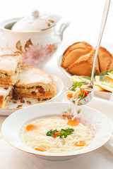 Traditional Tatar holiday table. Tokmach - noodle soup with chicken. Triangles - meat pies and sweet cake.