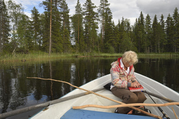 Women sitting in a rowing boat and looking for a new fishing bite, Picture from the North of Sweden.