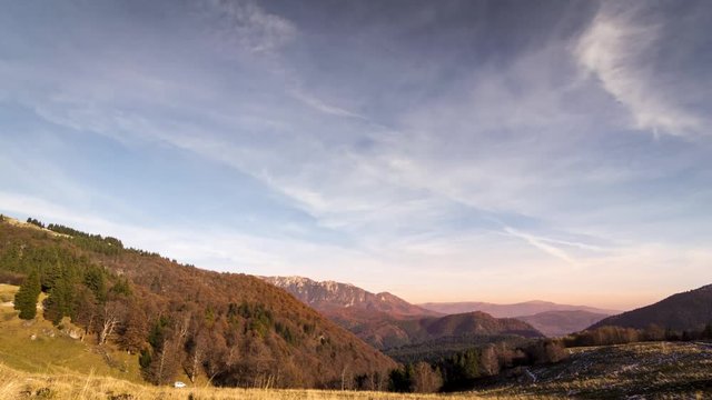 time lapse of sunset over colorful autumn forest with blue sky and mountain peaks
