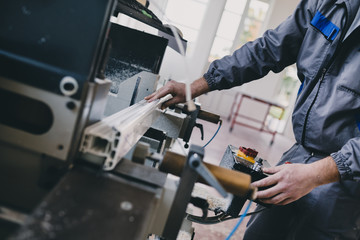 Manual worker cutting aluminum and PVC profiles. Manufacturing jobs. Selective focus. Factory for...