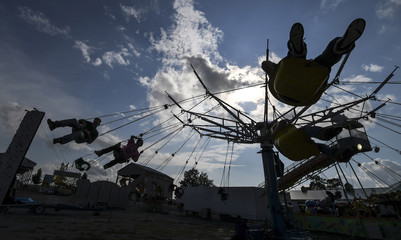 Riders are silhouetted on the swings in the midway Friday July 29, 2016., the 189th Whitaker Bank...