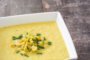 Corn soup in white bowl on wooden background
