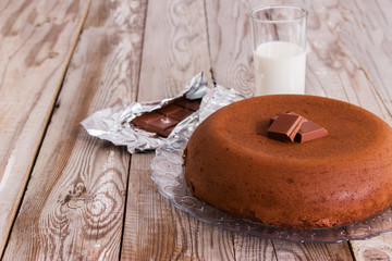 Chocolate-cottage cheese cake and milk on wooden background.