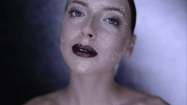 The girl's face is covered with gloss and glitter . Posing