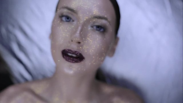 The girl's face is covered with gloss and glitter . Posing