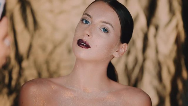 The girl's face is covered with gloss and glitter . Posing