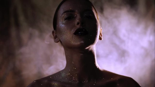 The girl's face is covered with gloss and glitter . Posing