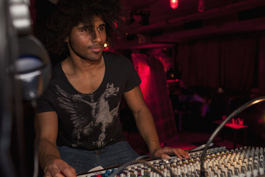 Young man playing DJ mixer in nightclub