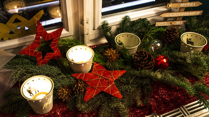Zweiter Advent / Adventsgesteck mit weihnachtlichen Kerzen, Weihnachtskugeln und Tannenzweigen auf Fensterbank