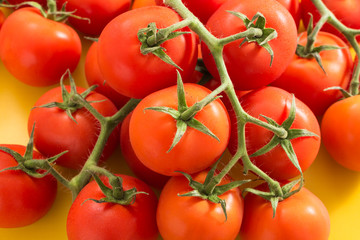 Heap of red cherry tomatoes with stem, closeup