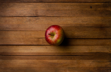 One organic small garden ripe red apple on wooden plank