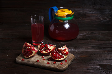pomegranate juice with sliced pomegranate on a wooden board.