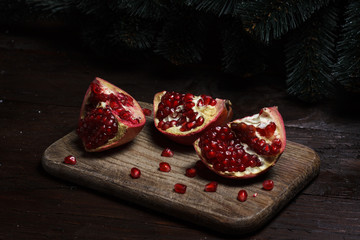 cut part of pomegranate on a wooden board on a wooden background on the background of trees. New Year's holiday. tree branch