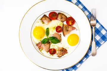 Fried eggs with bacon and vegetables on a white plate