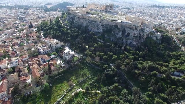 Aerial drone bird-eye view moving up for flight around the Acropolis of Athens ancient citadel located on rocky outcrop showing Parthenon very famous tourist attraction in Europe Greece great city 4k