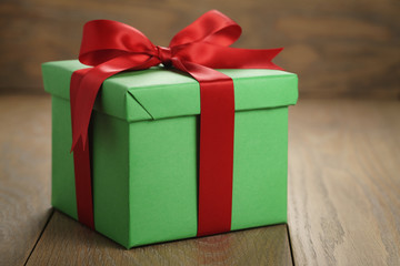 green paper gift box gift box with lid and red ribbon bow on wood table with copy space