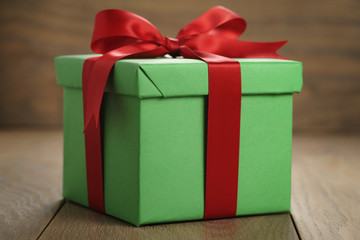green paper gift box gift box with lid and red ribbon bow on wood table