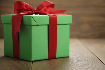green paper gift box gift box with lid and red ribbon bow on wood table with copy space