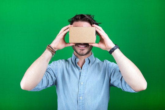 male holding cardboard virtual reality headset isolated on green