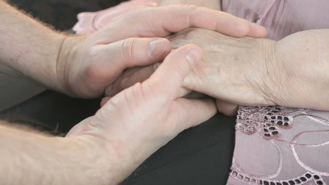 Man holding old wrinkled hands of elderly woman