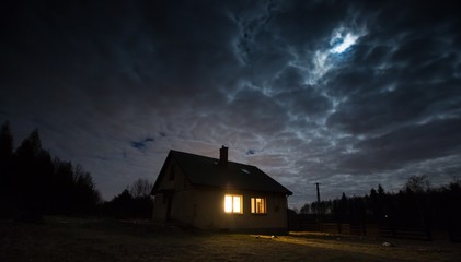 Landscape with house at night under cloudy sky