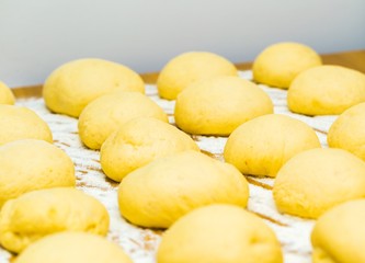 Raw donuts lying in flour on wooden table