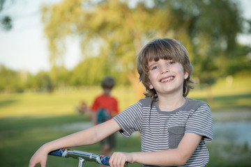 Fototapeta premium Portrait of young blonde boy in park with blurred background