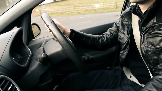 Young trendy male in leather jacket starting modern car and driving off.