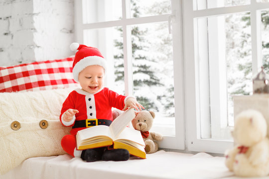happy baby dressed as Santa Claus sitting on window of house in