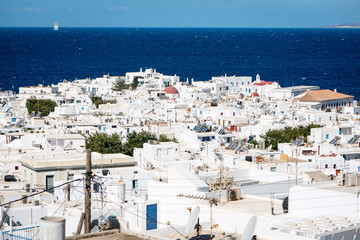 View over Mykonos town at noon with traditional sailing boat in