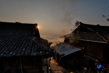 Sun rising behingtraditional Chinese minority houses