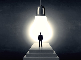Man standing on a step in front of a huge light bulb