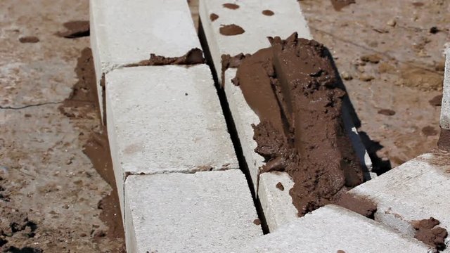 Bricklayer putting down a mix of cement to build a wall
