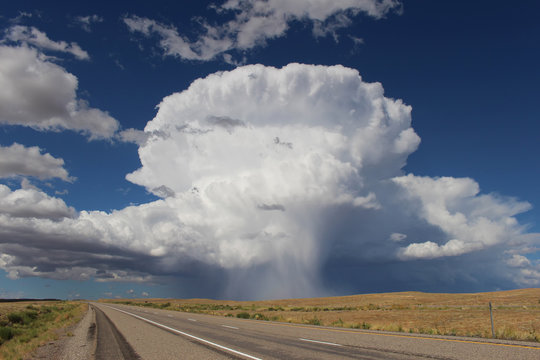 Isolated thunderstorm with sunlit precipitation shaft along Interstate 70 in Utah