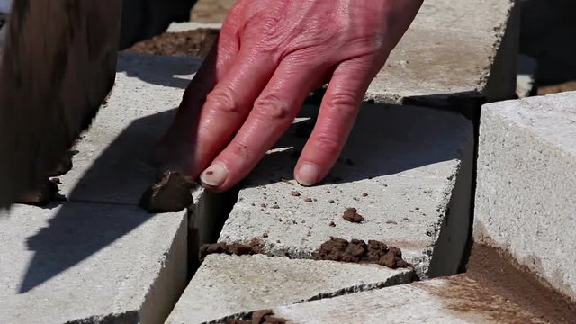 Closeup shot of a builder adding bricks to a wall
