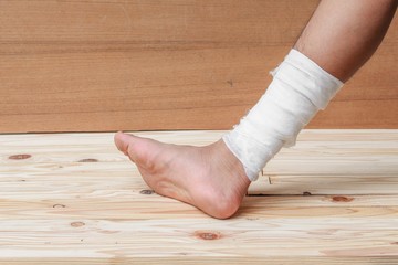 Gauze bandage the treating case with ankle Injured on wooden 