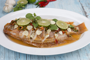 steamed fish with chili and lemon on blue wood table, thai food