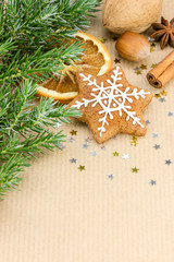 homemade christmas spice cookies, nuts, fruits, green fir tree branch on brown background