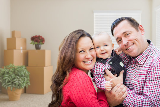 Happy Caucasian Family with Baby In Room with Moving Boxes.
