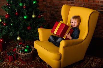 Obraz na płótnie Canvas The child with a gift near the Christmas tree