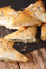 triangles of phyllo pastry stuffed with chicken, spinach and cheese close-up. vertical
