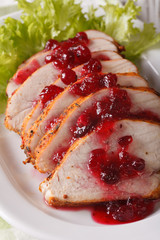 Sliced roasted turkey breast with cranberry sauce close-up. vertical