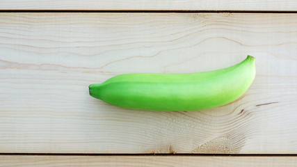 Green banana on wooden background.