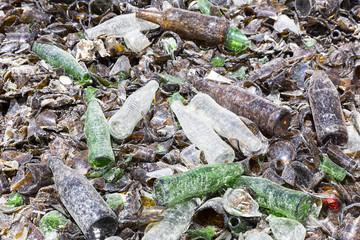 Glass waste in recycling facility. Brown and green bottles.