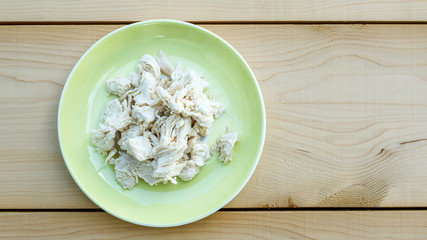 Boiled chicken meat in a yellow plate on wooden background.
