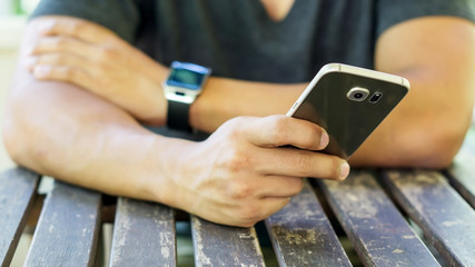 hand using a smartphone and a smartwatch.