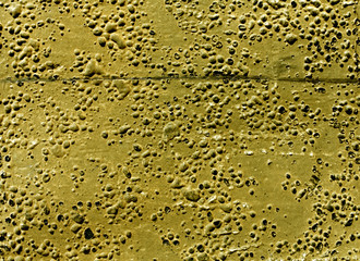 Grungy yellow rubber surface with bubbles and scratches.