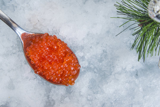 Spoon with salmon roe on snow background. Top view, with copy space